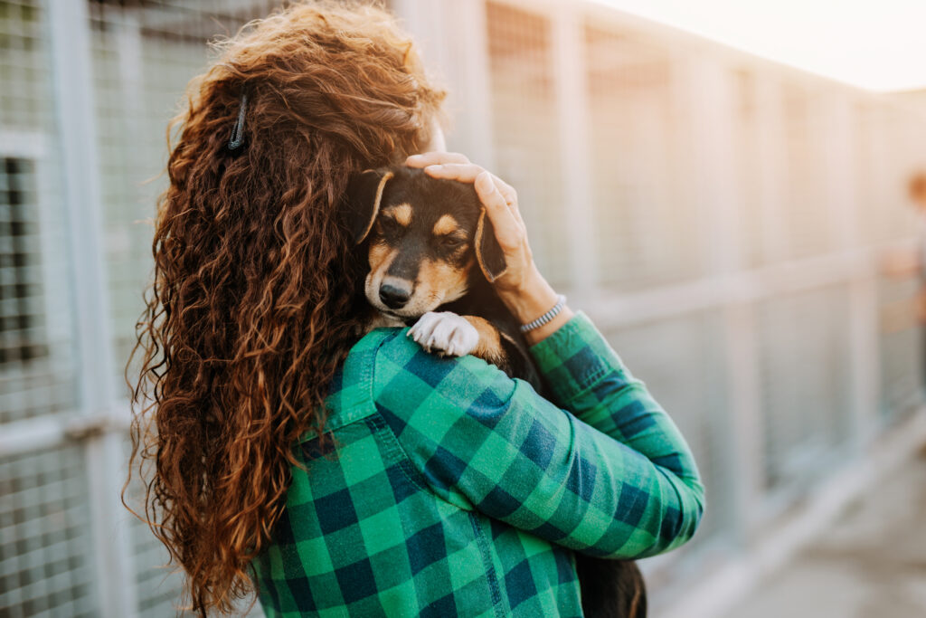 Frau hält einen Hund im Arm und lächelt