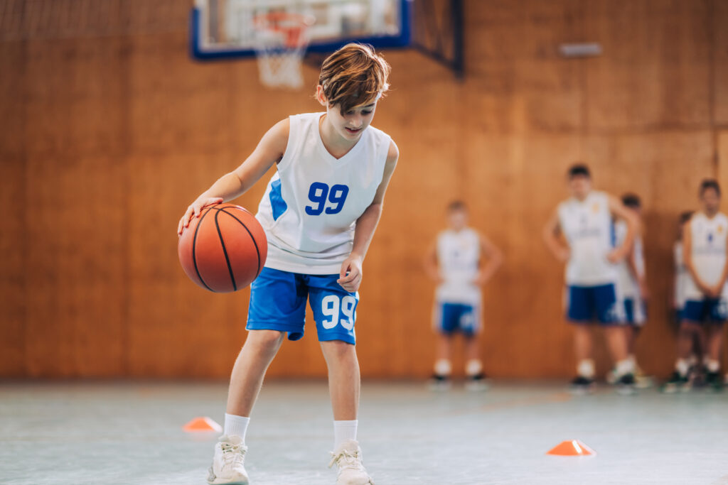 Junger Mann spielt Basketball in einer Halle
